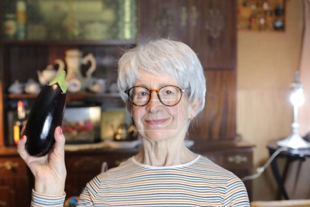Foto de Close-up portrait of mature woman with eggplant at home - Imagen libre de derechos