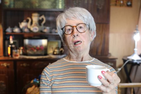Photo for Close-up portrait of mature woman with cup of hot drink at home - Royalty Free Image