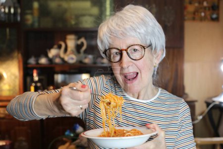 Photo for Close-up portrait of mature woman with plate of spaghetti at home - Royalty Free Image
