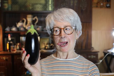 Photo for Close-up portrait of mature woman with eggplant at home - Royalty Free Image