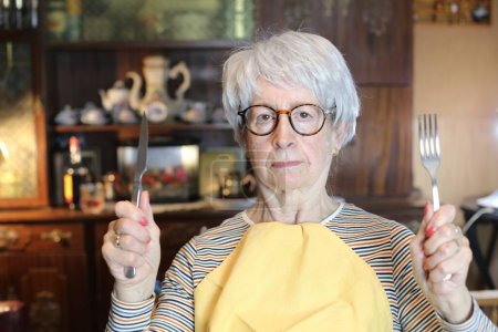 Foto de Close-up portrait of mature woman with cutlery and napkin at home - Imagen libre de derechos