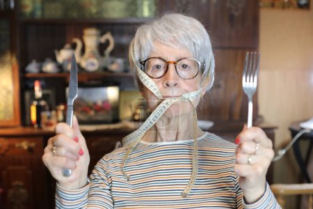 Foto de Close-up portrait of mature woman with cutlery and measuring tape at home - Imagen libre de derechos
