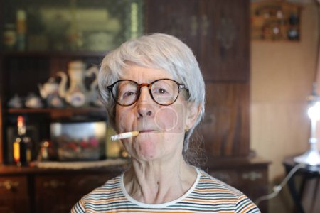 Photo for Close-up portrait of mature woman with cigarette at home - Royalty Free Image