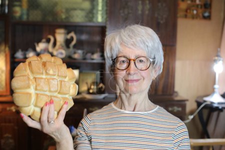 Photo for Close-up portrait of mature woman with freshly baked bread at home - Royalty Free Image