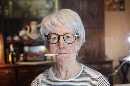 Téléchargez les photos : Close-up portrait of mature woman with cigarette smoking at home - en image libre de droit
