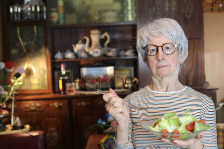 Téléchargez les photos : Close-up portrait of mature woman with bowl of salad at home - en image libre de droit