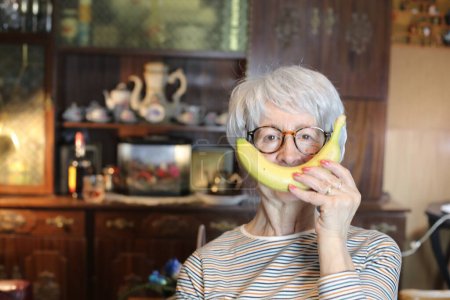 Photo for Close-up portrait of mature woman with banana at home - Royalty Free Image