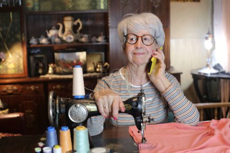 Foto de Close-up portrait of mature woman with vintage sewing machine at home - Imagen libre de derechos