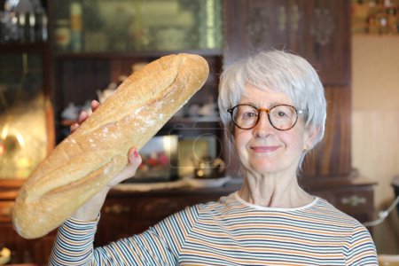 Téléchargez les photos : Close-up portrait of mature woman with freshly baked bread at home - en image libre de droit