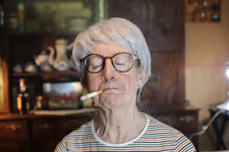 Foto de Close-up portrait of mature woman smoking cigarette at home - Imagen libre de derechos