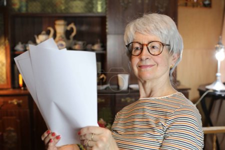 Téléchargez les photos : Close-up portrait of mature woman with lots of papers at home - en image libre de droit