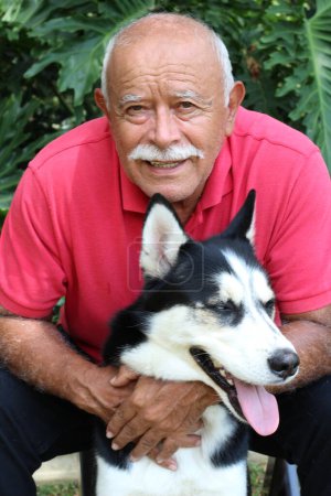 Foto de Close-up portrait of happy mature man with his husky dog in park - Imagen libre de derechos