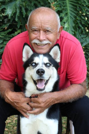Téléchargez les photos : Close-up portrait of happy mature man with his husky dog in park - en image libre de droit