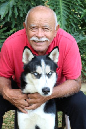 Foto de Close-up portrait of happy mature man with his husky dog in park - Imagen libre de derechos