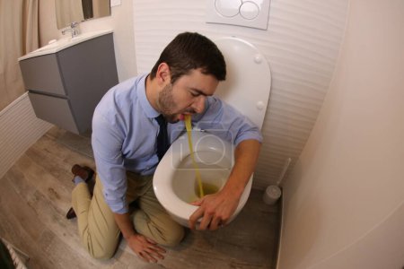 Foto de Wide angle shot of young man vomiting in toilet - Imagen libre de derechos