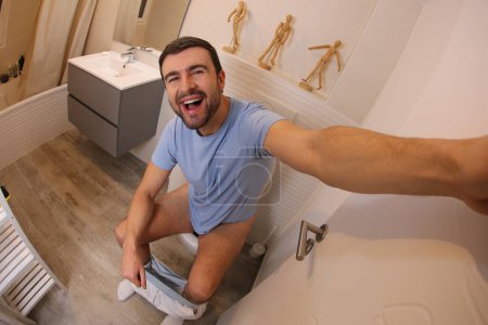 Téléchargez les photos : Plan grand angle de jeune homme prenant selfie dans les toilettes - en image libre de droit