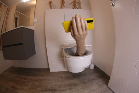 Téléchargez les photos : Plan grand angle de la main avec smartphone qui sort des toilettes, concept comique - en image libre de droit
