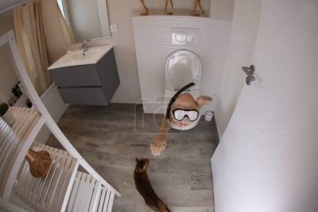 Foto de Wide angle shot of person with snorkel and diving mask sticking out of toilet, comedy concept - Imagen libre de derechos