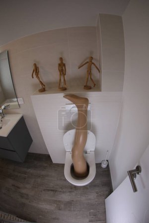 Foto de Wide angle shot of plastic leg sticking out of toilet - Imagen libre de derechos