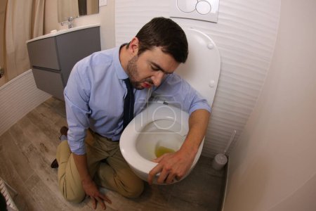 Photo for Wide angle shot of young man vomiting in toilet - Royalty Free Image