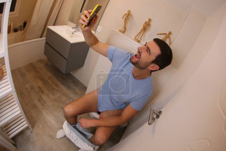 Téléchargez les photos : Plan grand angle de jeune homme avec smartphone dans les toilettes - en image libre de droit