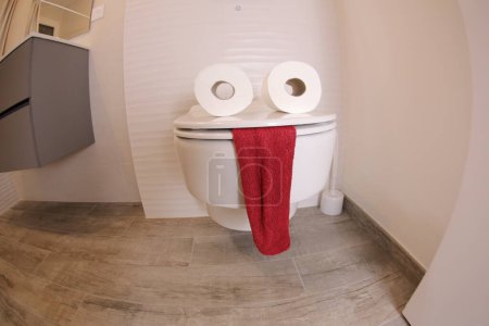 Photo for Wide angle shot of toilet with face made of paper rolls and red towel, comedy concept - Royalty Free Image