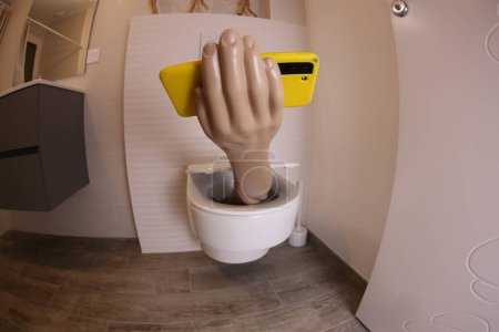 Photo for Wide angle shot of hand with smartphone sticking out of toilet, comedy concept - Royalty Free Image