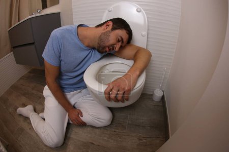 Foto de Amplio ángulo de tiro de hombre joven vomitando en el inodoro - Imagen libre de derechos