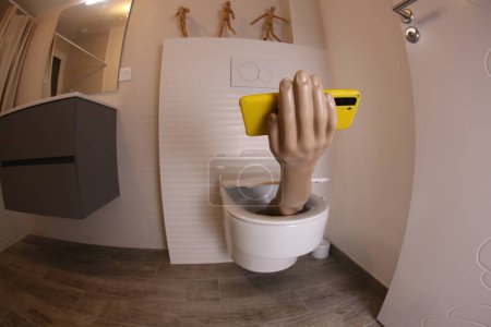Foto de Wide angle shot of hand with smartphone sticking out of toilet, comedy concept - Imagen libre de derechos