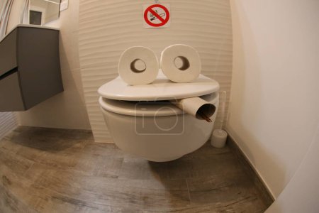 Foto de Wide angle shot of smoking toilet face made with paper rolls, comedy concept - Imagen libre de derechos
