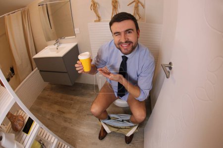 Téléchargez les photos : Plan grand angle de jeune homme avec tasse en papier de café dans les toilettes - en image libre de droit