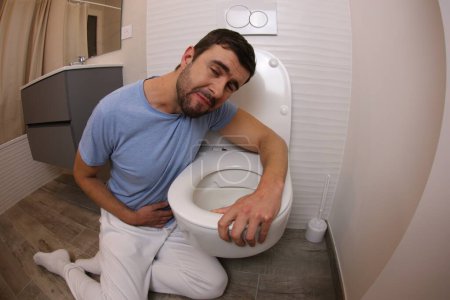Foto de Amplio ángulo de tiro de hombre joven vomitando en el inodoro - Imagen libre de derechos