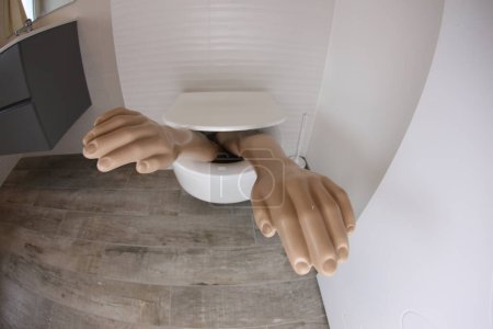 Téléchargez les photos : Wide angle shot of plastic arms sticking out of toilet - en image libre de droit