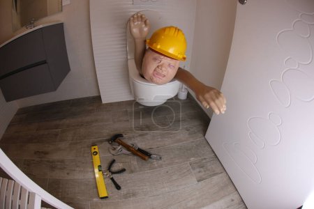 Photo for Wide angle shot of person with hard hat sticking out of toilet, comedy concept - Royalty Free Image