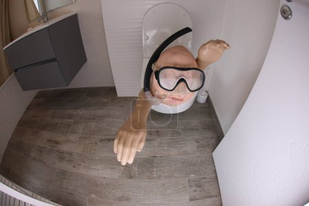 Téléchargez les photos : Wide angle shot of person with snorkel and diving mask sticking out of toilet, comedy concept - en image libre de droit