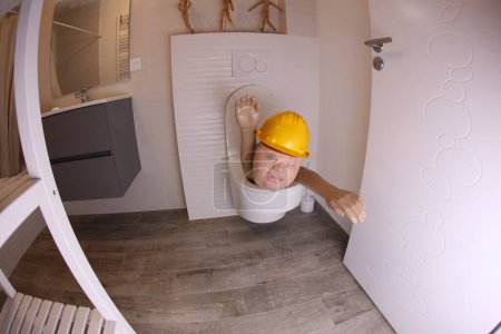 Téléchargez les photos : Plan grand angle de la personne avec un chapeau dur qui sort des toilettes, concept comique - en image libre de droit