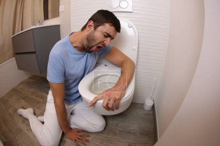 Téléchargez les photos : Plan grand angle de jeune homme vomissant dans les toilettes - en image libre de droit