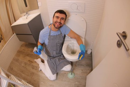 Photo for Wide angle shot of young man cleaning toilet - Royalty Free Image