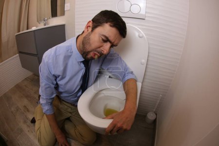 Téléchargez les photos : Plan grand angle de jeune homme vomissant dans les toilettes - en image libre de droit