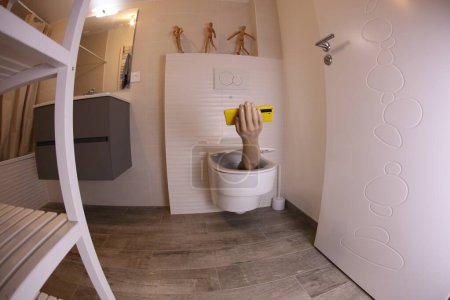 Téléchargez les photos : Plan grand angle de la main avec smartphone qui sort des toilettes, concept comique - en image libre de droit