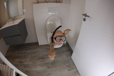 Téléchargez les photos : Plan grand angle de la personne avec tuba et masque de plongée sortant des toilettes, concept comique - en image libre de droit