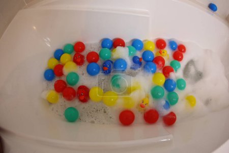 Photo for Close-up shot of bathtub with foam, colorful rubber ducks and balls - Royalty Free Image