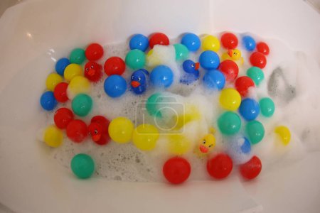 Téléchargez les photos : Gros plan de la baignoire avec mousse, canards et boules en caoutchouc coloré - en image libre de droit