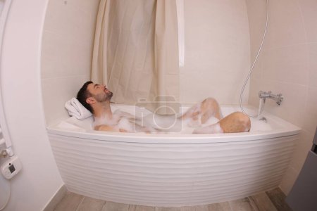 Téléchargez les photos : Plan grand angle de beau jeune homme dans le bain - en image libre de droit
