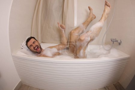Téléchargez les photos : Plan grand angle de beau jeune homme s'amusant dans le bain - en image libre de droit