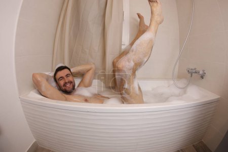 Foto de Wide angle shot of handsome young man having fun in bath - Imagen libre de derechos