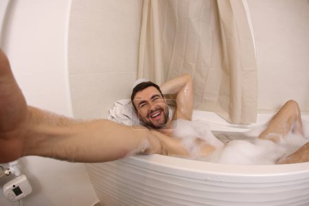 Téléchargez les photos : Wide angle shot of handsome young man talking selfie in bath - en image libre de droit