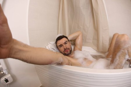 Téléchargez les photos : Wide angle shot of handsome young man talking selfie in bath - en image libre de droit