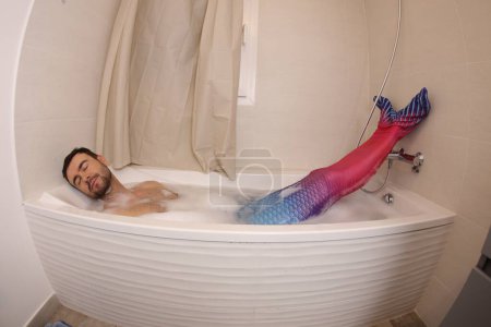 Téléchargez les photos : Plan grand angle de beau jeune homme en costume de sirène dans le bain - en image libre de droit
