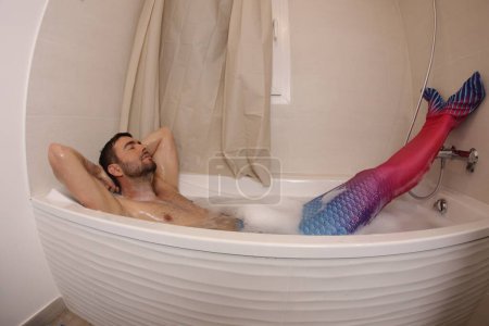 Foto de Wide angle shot of handsome young man in mermaid costume in bath - Imagen libre de derechos